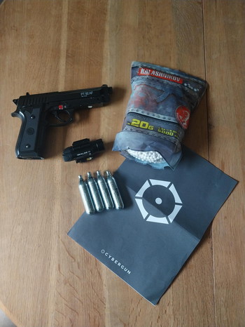 Bild 2 für Cybergun PT92 AF 6mm met Weapon light Olight Baldr Pro, zak met balletjes en 4 Cartouches CO2