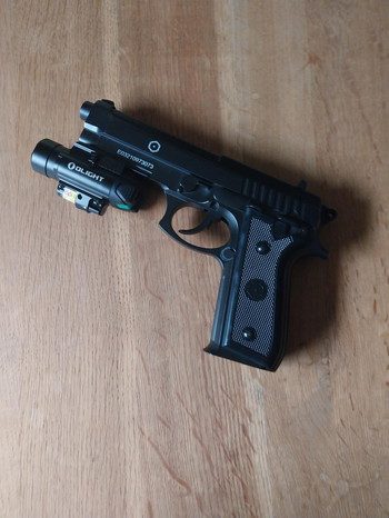 Bild 3 für Cybergun PT92 AF 6mm met Weapon light Olight Baldr Pro, zak met balletjes en 4 Cartouches CO2